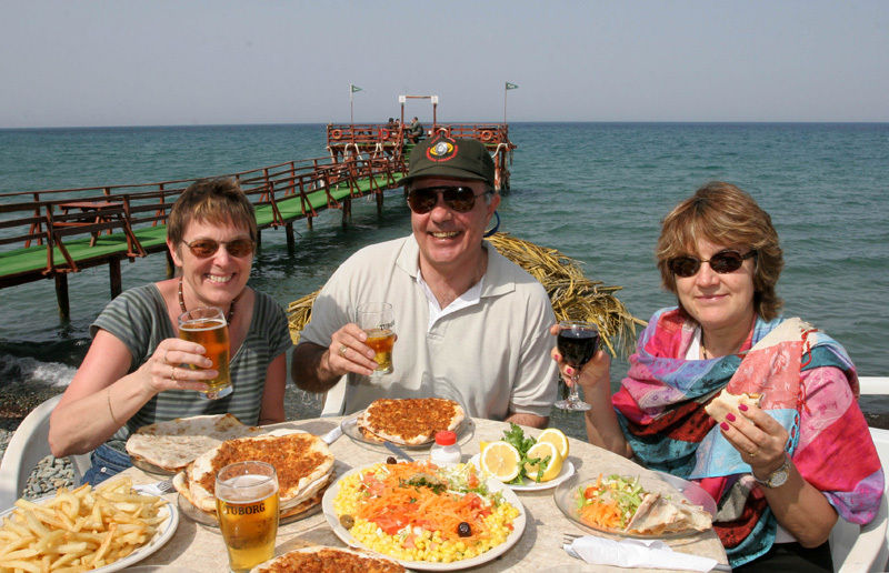 Single travellers enjoying a Spanish meal together by the sea