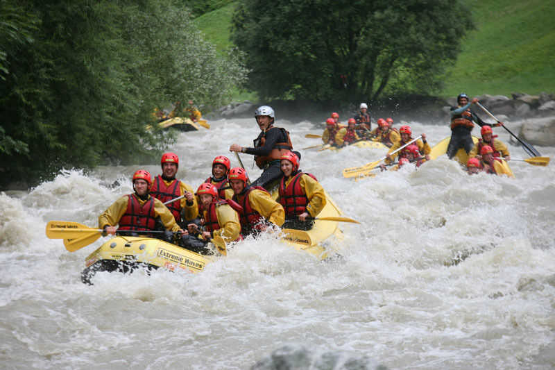 Single travellers on holiday white water rafting together
