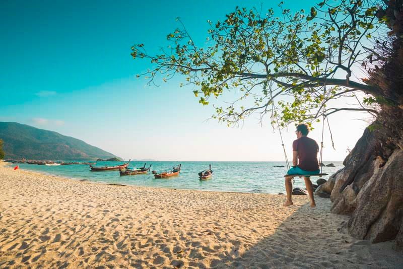 Single man sitting on a swing alone on a beach