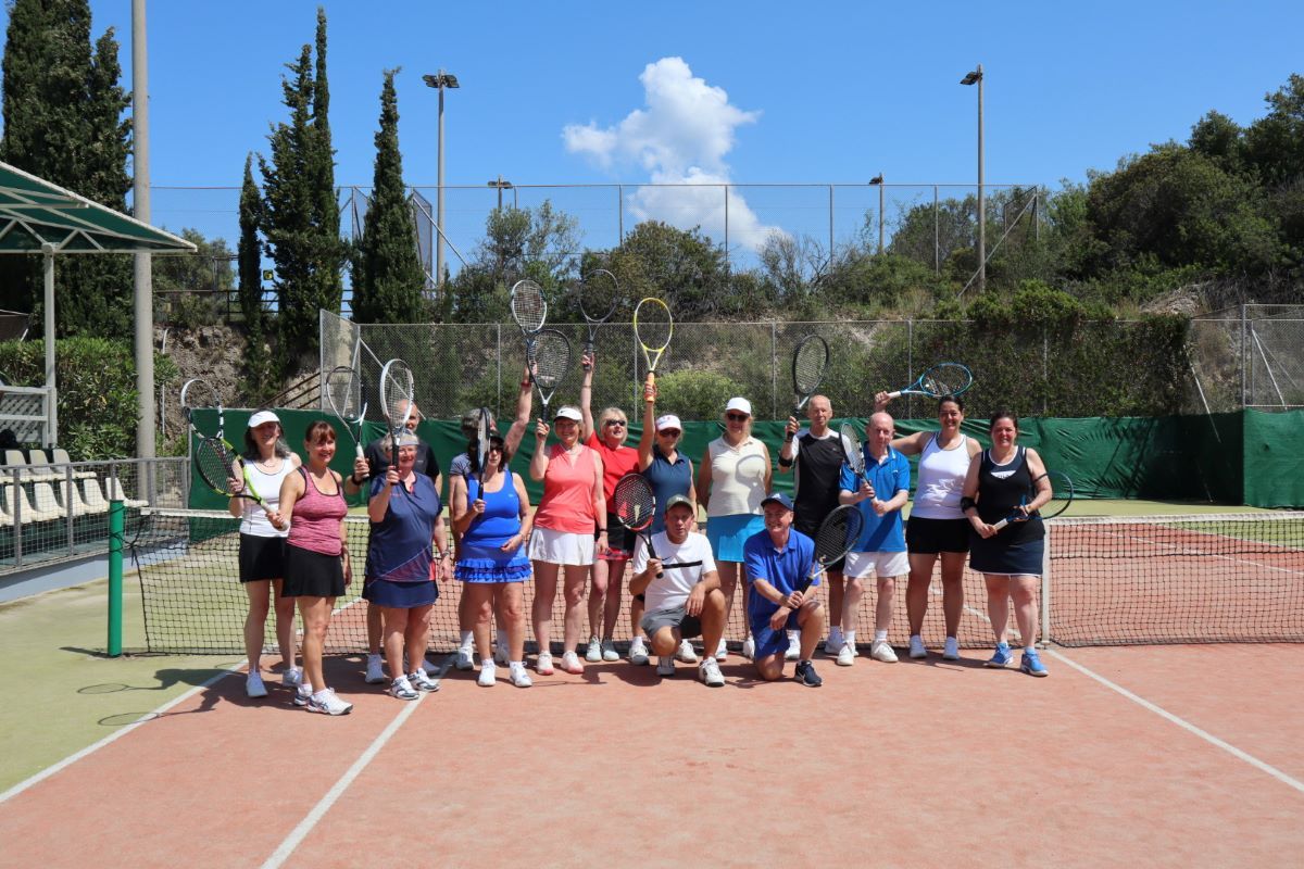 A group of people smiling with tennis rackets in Grecotel Daphnila Bay, Corfu tennis court.