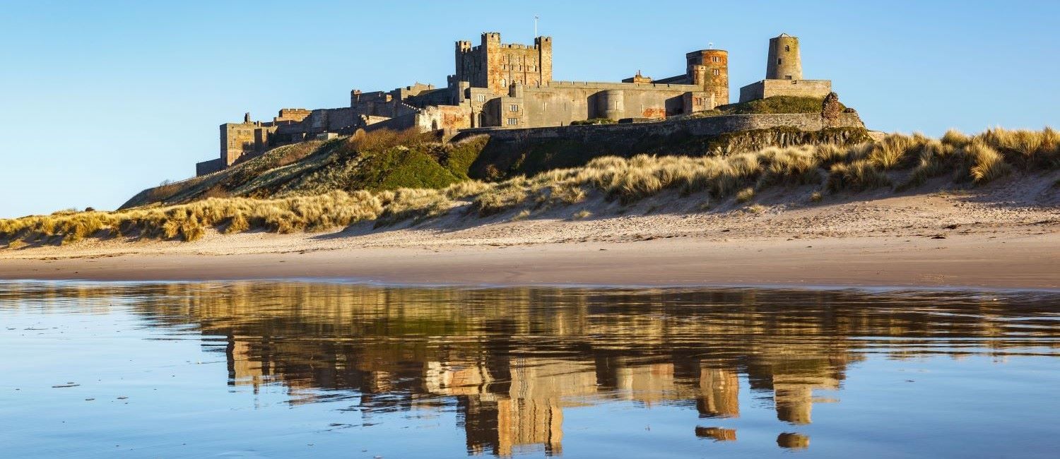 A deserted beach and sea sitting next to Bamburgh Castle Northumberland England