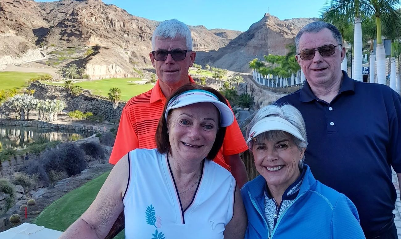 Four people smiling outside playing golf on Anfi Taruo golf resort in Gran Canaria.