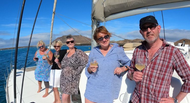 Four people smiling on a boat holding a glass of wine