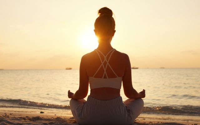 woman meditating on beach